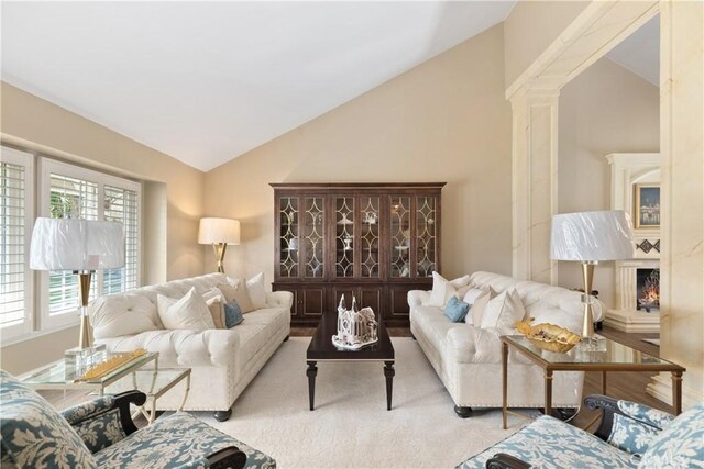 carpeted living area with vaulted ceiling and decorative columns