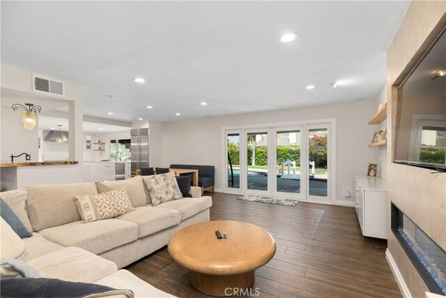 living area featuring recessed lighting, baseboards, visible vents, and dark wood-type flooring