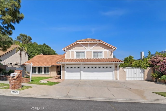 mediterranean / spanish-style home featuring a gate, stucco siding, a tiled roof, and concrete driveway
