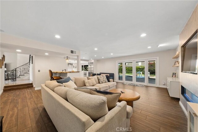 living area featuring dark wood finished floors, stairway, visible vents, and baseboards