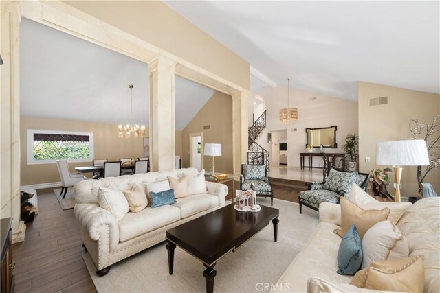 living room featuring wood finished floors, visible vents, baseboards, a chandelier, and high vaulted ceiling