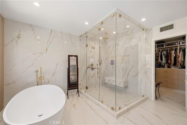 bathroom featuring a spacious closet, marble finish floor, visible vents, a marble finish shower, and a soaking tub