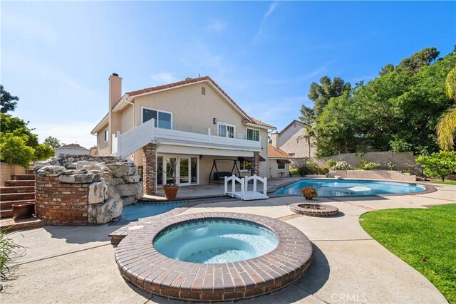 rear view of house featuring a patio area, a chimney, a fenced in pool, an in ground hot tub, and stucco siding