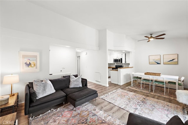 living room featuring ceiling fan, baseboards, lofted ceiling, and light wood-style floors