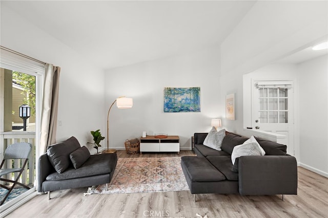 living area with baseboards, vaulted ceiling, and wood finished floors
