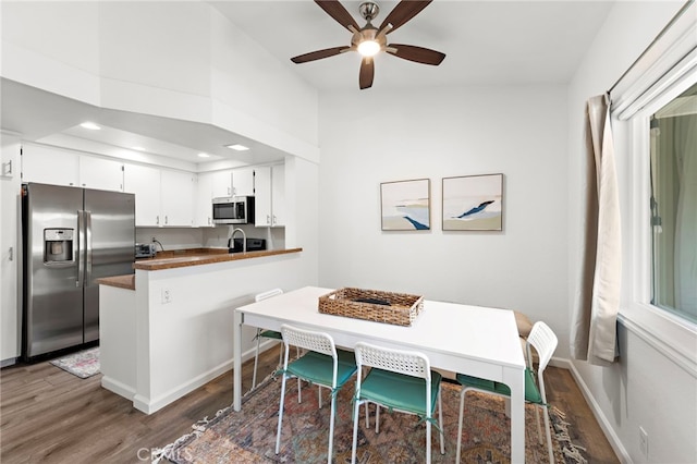 kitchen with dark countertops, stainless steel appliances, a peninsula, and wood finished floors
