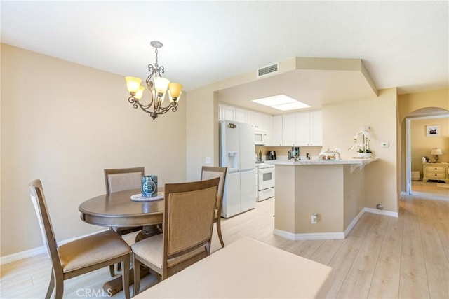 dining area featuring visible vents, arched walkways, light wood-style flooring, and a chandelier