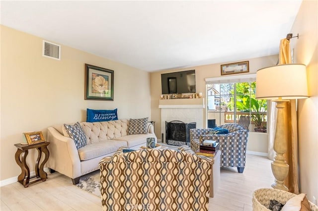 living room with baseboards, a brick fireplace, light wood-type flooring, and visible vents