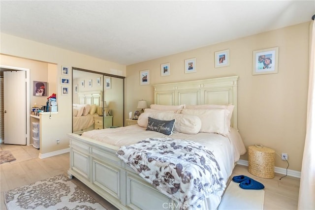 bedroom featuring light wood-type flooring, baseboards, and a closet