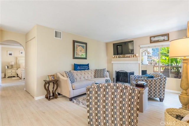 24352 Berrendo Unit 4, Aliso Viejo, CA 92656 - living area with a tiled fireplace, arched walkways, light wood finished floors, and baseboards