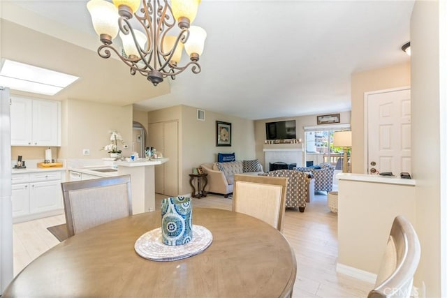24352 Berrendo Unit 4, Aliso Viejo, CA 92656 - dining space featuring light wood-type flooring, a fireplace, and a chandelier