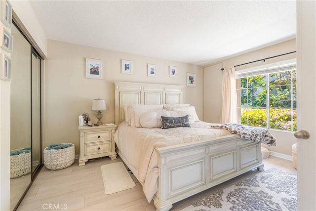 bedroom featuring baseboards, a closet, and light wood-style flooring