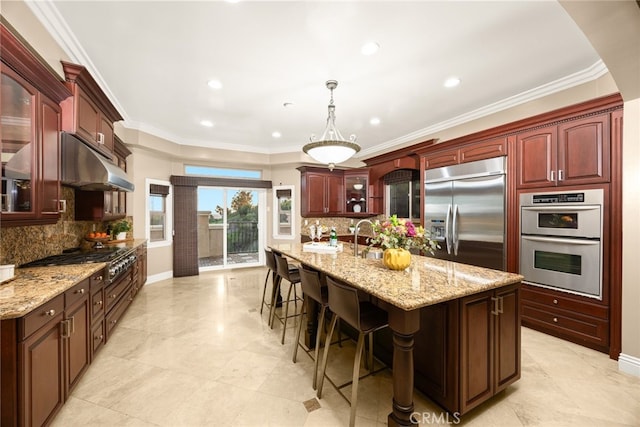 15841 Aurora Crest Dr, Whittier, CA 90605 - kitchen featuring appliances with stainless steel finishes, under cabinet range hood, reddish brown cabinets, tasteful backsplash, and recessed lighting
