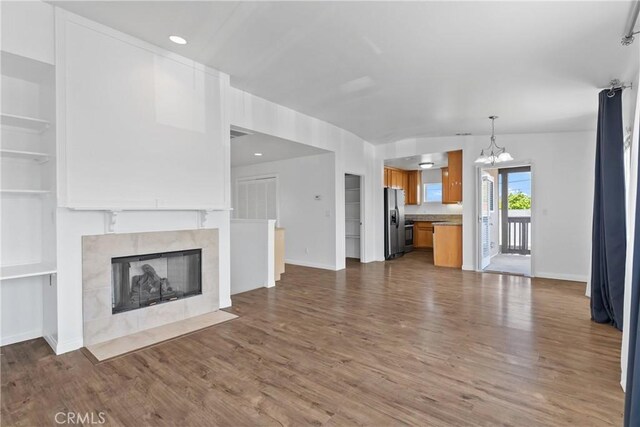 247 W 223rd St Unit D, Carson, CA 90745 - unfurnished living room featuring dark wood-style floors, a chandelier, a tile fireplace, baseboards, and built in shelves