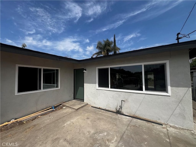 entrance to property featuring a patio and stucco siding