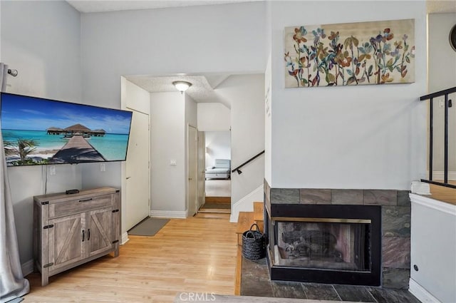 living area with baseboards, wood finished floors, and stairway