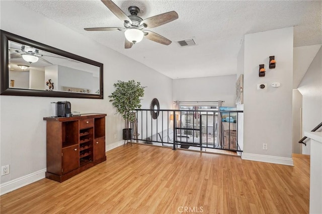 interior space with baseboards, a ceiling fan, wood finished floors, and a textured ceiling