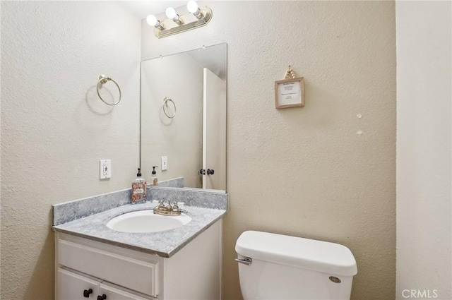 half bath featuring vanity and toilet