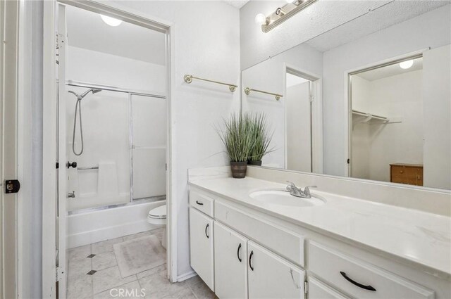 bathroom featuring a walk in closet, combined bath / shower with glass door, toilet, and vanity