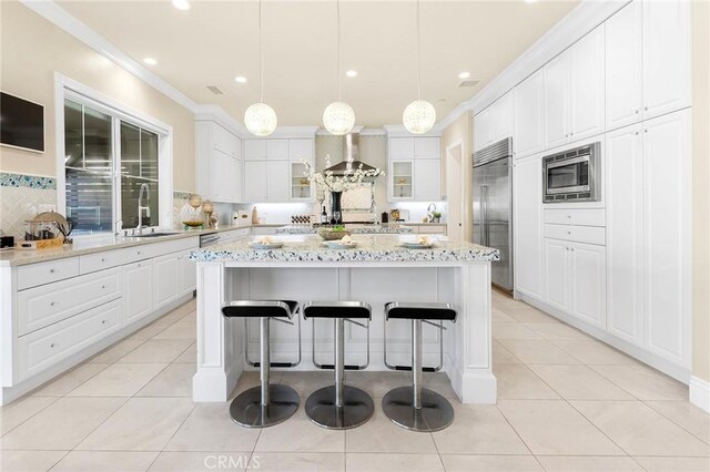 123 Calderon, Irvine, CA 92618 - kitchen featuring wall chimney range hood, crown molding, a sink, light tile patterned flooring, and built in appliances