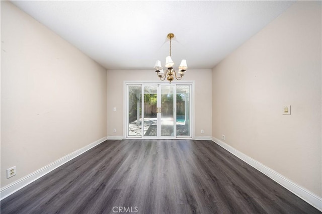 unfurnished dining area featuring a chandelier, dark wood-type flooring, and baseboards