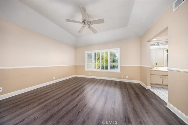 spare room with wood finished floors, a ceiling fan, and baseboards