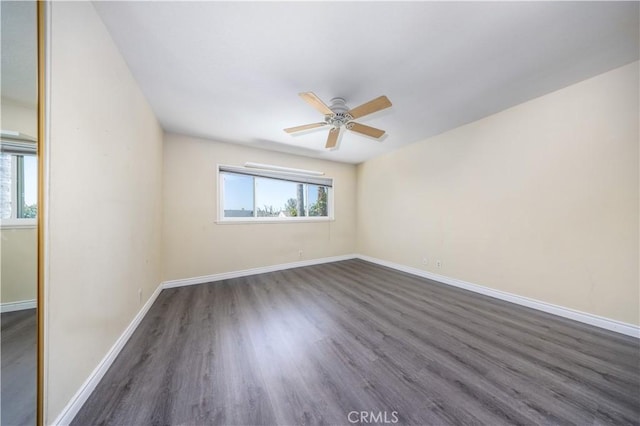 unfurnished room with ceiling fan, dark wood-type flooring, and baseboards