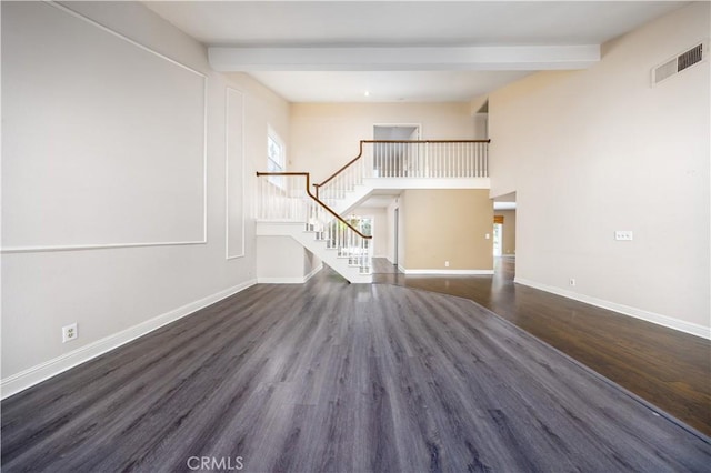 unfurnished living room with beam ceiling, wood finished floors, stairway, baseboards, and a high ceiling