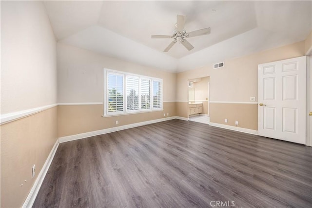 empty room featuring a ceiling fan, wood finished floors, a tray ceiling, and baseboards