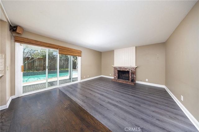 unfurnished living room with dark wood-style flooring, a fireplace, and baseboards