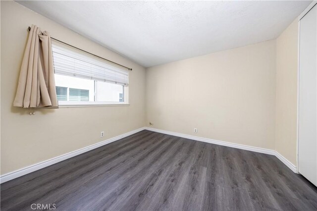 empty room with dark wood finished floors and baseboards
