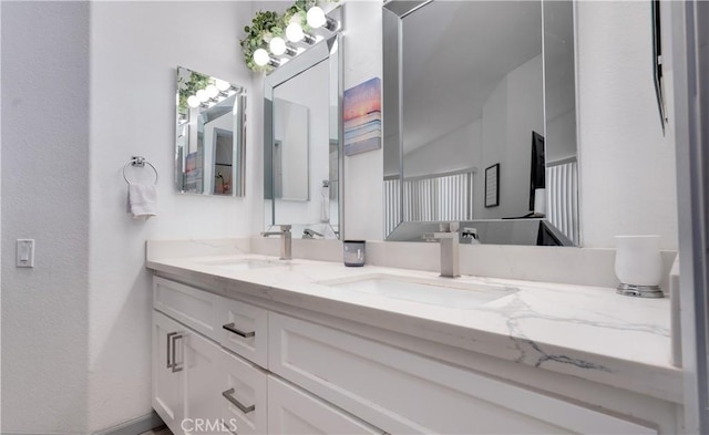 full bath featuring double vanity, a textured wall, and a sink