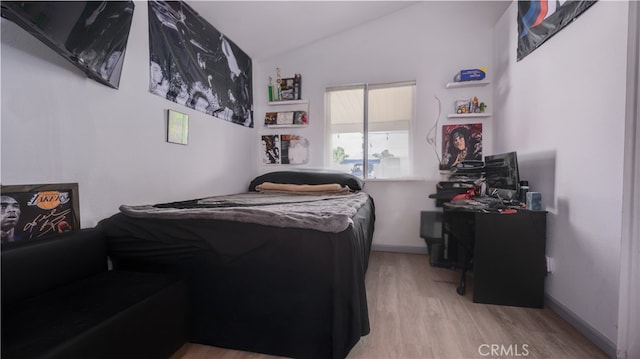 bedroom with vaulted ceiling and wood finished floors