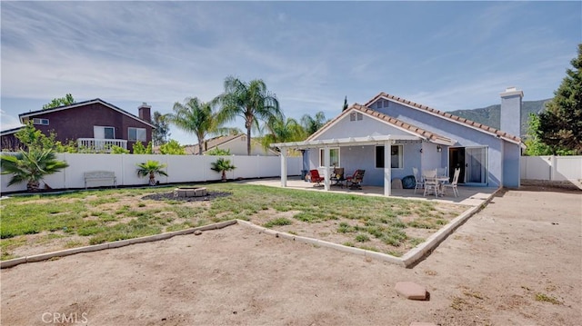 rear view of property with a fenced backyard, a pergola, a chimney, a patio area, and stucco siding