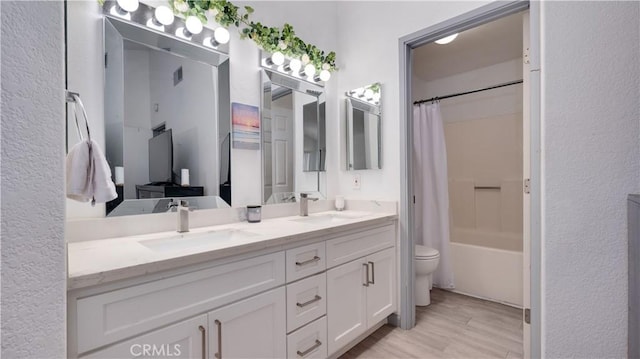 bathroom featuring double vanity, toilet, wood finished floors, and a sink