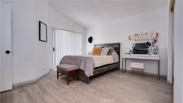 bedroom with lofted ceiling, light wood finished floors, and baseboards