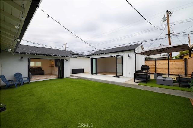 rear view of house featuring an outdoor structure, a yard, a patio, and fence