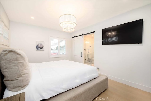 bedroom featuring a barn door, baseboards, wood finished floors, and recessed lighting