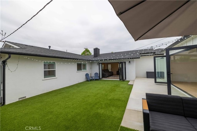 back of property featuring stucco siding, a chimney, a patio area, and a lawn