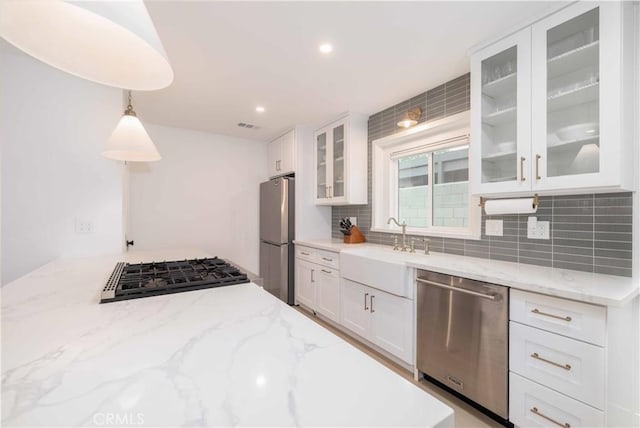 kitchen with decorative backsplash, a sink, white cabinetry, and appliances with stainless steel finishes