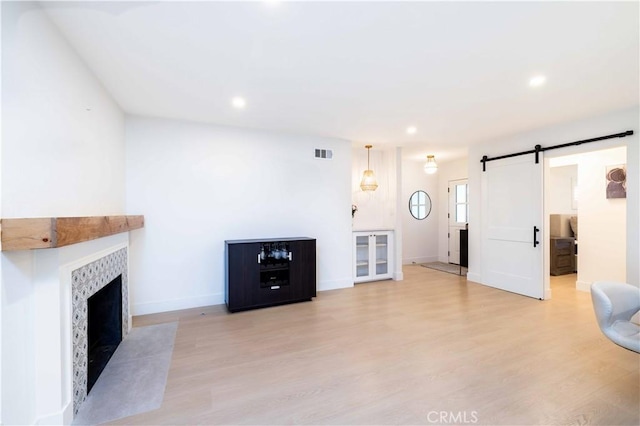 unfurnished living room featuring light wood-style flooring, visible vents, recessed lighting, and a barn door