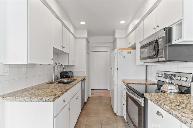 kitchen featuring decorative backsplash, appliances with stainless steel finishes, a sink, and white cabinets