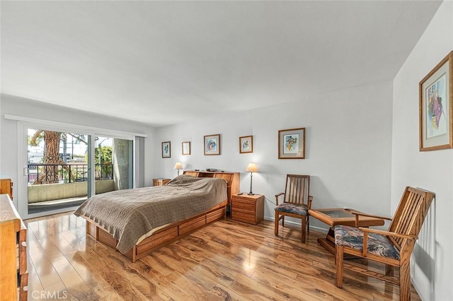 bedroom with access to outside and wood finished floors