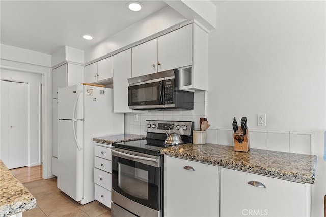 kitchen featuring white cabinets, recessed lighting, light tile patterned floors, tasteful backsplash, and appliances with stainless steel finishes