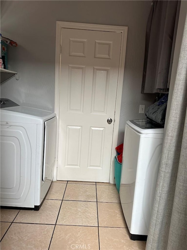 washroom with washing machine and dryer, laundry area, and light tile patterned floors