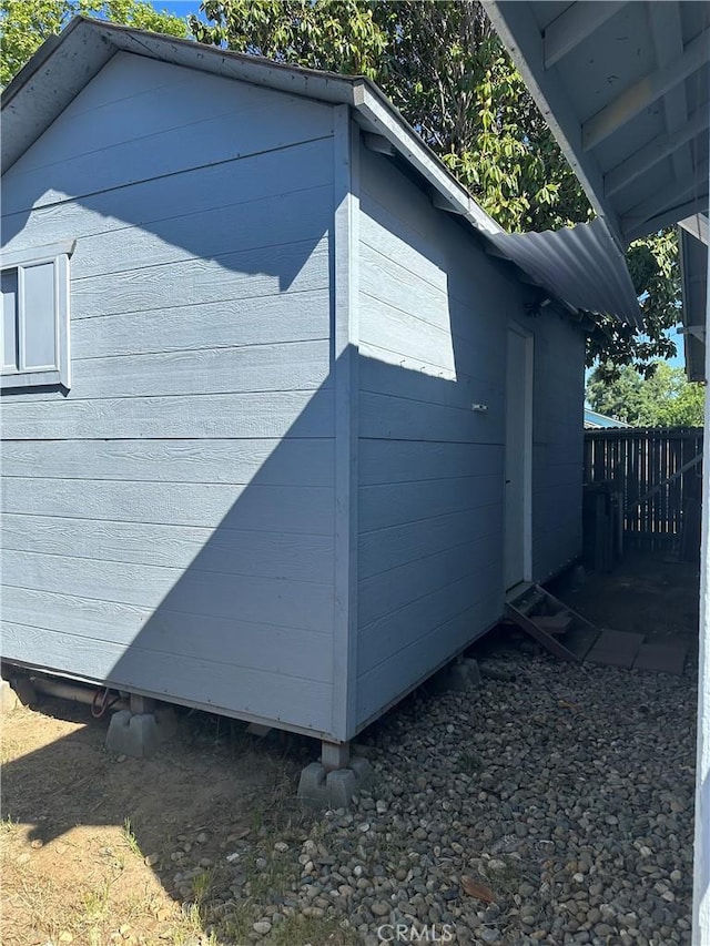 view of side of home featuring an outbuilding and fence