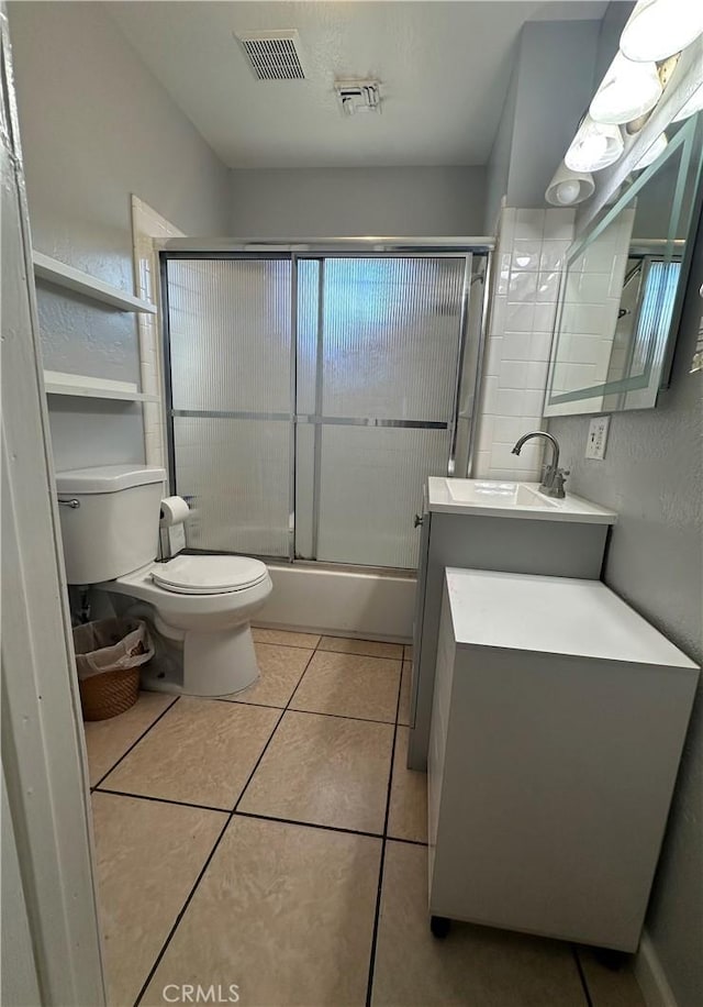 bathroom with vanity, toilet, bath / shower combo with glass door, and visible vents