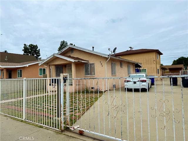 bungalow-style home featuring a front lawn, a gate, a fenced front yard, and stucco siding
