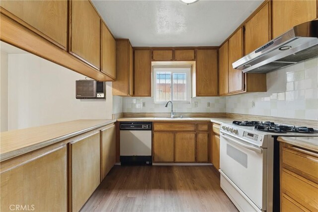 kitchen featuring a sink, white appliances, light countertops, under cabinet range hood, and dark wood-type flooring