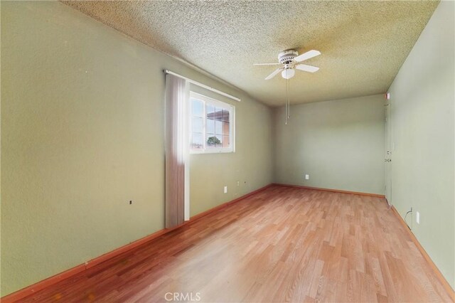 unfurnished room with a textured ceiling, light wood finished floors, and a ceiling fan